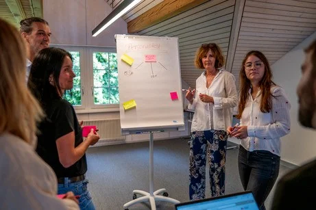 Mitarbeitende des Kinderdorf Pestalozzi stehen vor einer Flip-Chart.