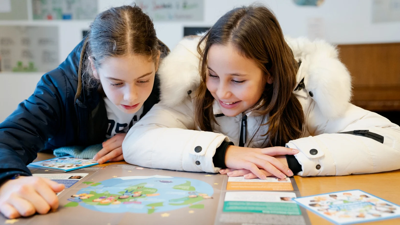 zwei kinder sitzen am tisch und beschäftigen sich mit einem projekt
